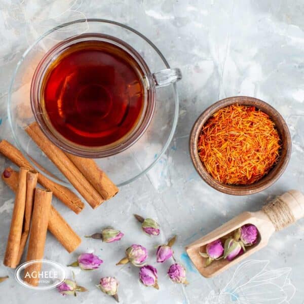 دم کردن زعفران-چای زعفرانی در لیوان شیشه ای که کنار آن دارچین و گل محمدی است3