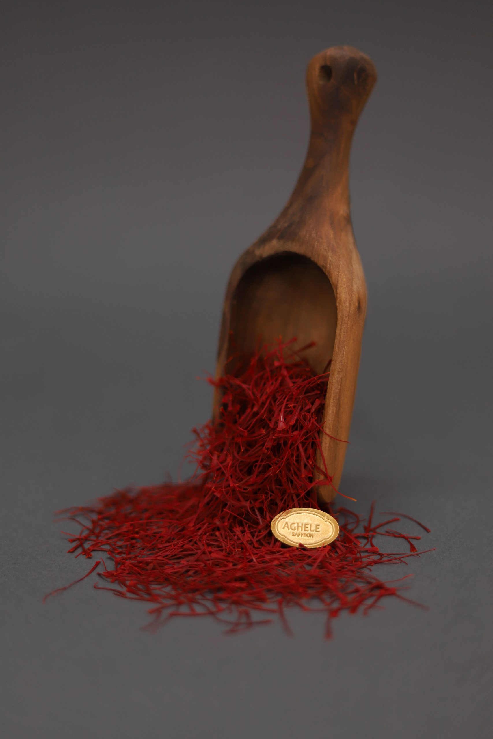 خرید زعفران نگین عاقله. زعفران که در حال ریختن از قاشق چوبی است