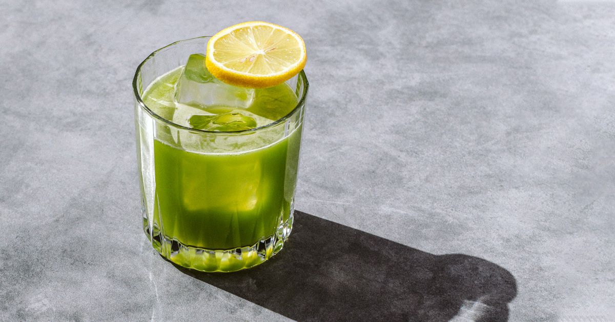 نوشیدنی سبز در لیوان به همراه یخ که روی آن یه تکه لیمو است