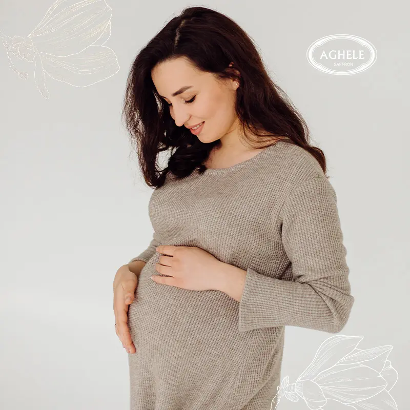 تاثیر زعفران در بارداری. خانومی باردار که دستانش روی شکمش است.